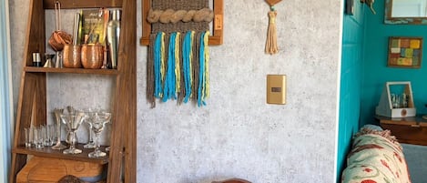 Una habitación con repisas de madera que sostienen cristalería y un tapiz de pared tejido.