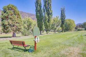 Un parque con un banco, un cartel verde y árboles.