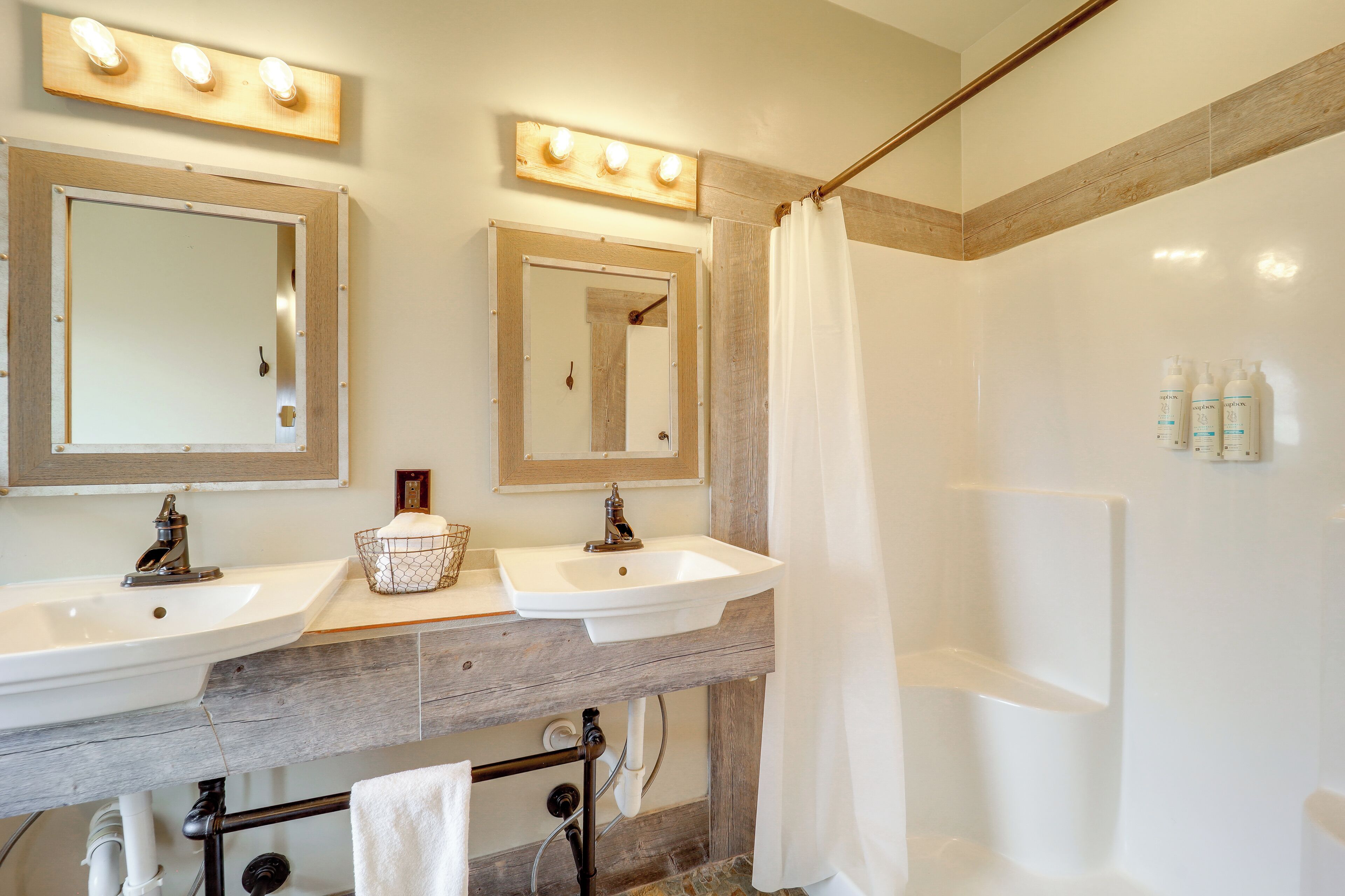 A bathroom with two sinks, a mirror, and a shower area.