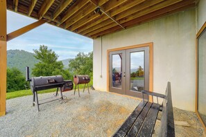 Una terrazza esterna con tetto in legno, due barbecue e una panchina.