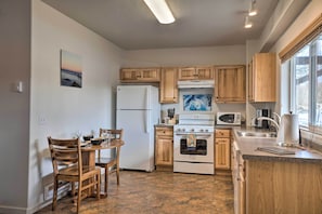 A kitchen with wooden cabinets, a refrigerator, an oven, a microwave, and a dining area with chairs and a table.