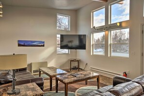 A living room with a large flat-screen TV, leather sofas, a coffee table, and a lamp.
