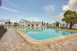 A swimming pool with a brick deck, surrounded by palm trees and a two-story building with a grey roof. - Walk to Englewood Beach! Resort-style Villa (Englewood)