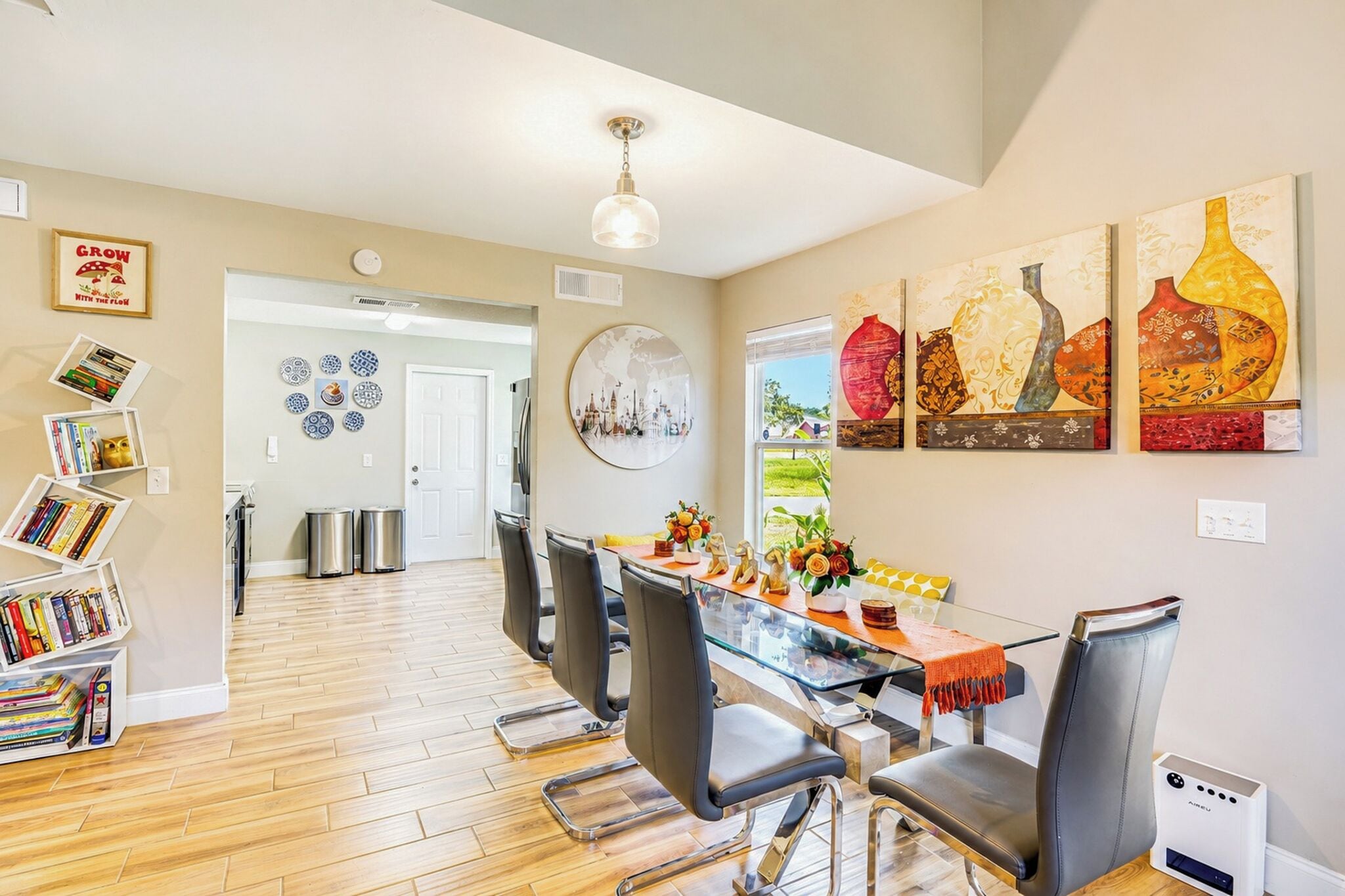 A modern kitchen with a dining area, wooden flooring, and a view to the outdoors.