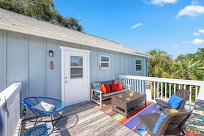 A covered outdoor area with a wooden deck, a seating area with a table and chairs, and a small window. - 13 Mi to Beach! Family-friendly Palm Bay Retreat (Palm Bay)