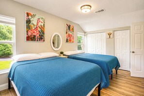 Ein Schlafzimmer mit zwei Betten, einem Spiegel und Bildern an den Wänden.