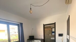 Quarto de hotel com cama, uma kitchenette compacta, janela com cortinas e vista para o exterior.