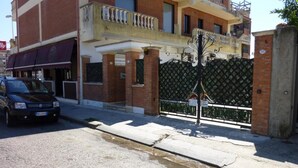Um edifício com fachada de tijolos, uma varanda com balaústres e uma entrada com portão.