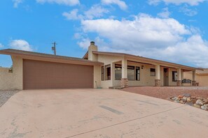 Ein eingeschossiges Haus mit Garage und überdachter Veranda, strahlend blauer Himmel.