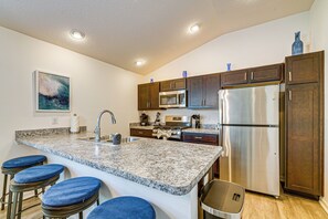 A modern kitchen with granite countertops, stainless steel appliances, and dark wooden cabinets. - Community Pools, Golf & More! Home in The Villages (Wildwood)
