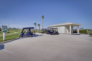 A golf cart parking area with a building labeled "6772" and a signboard in the background. - Community Pools, Golf & More! Home in The Villages (Wildwood)