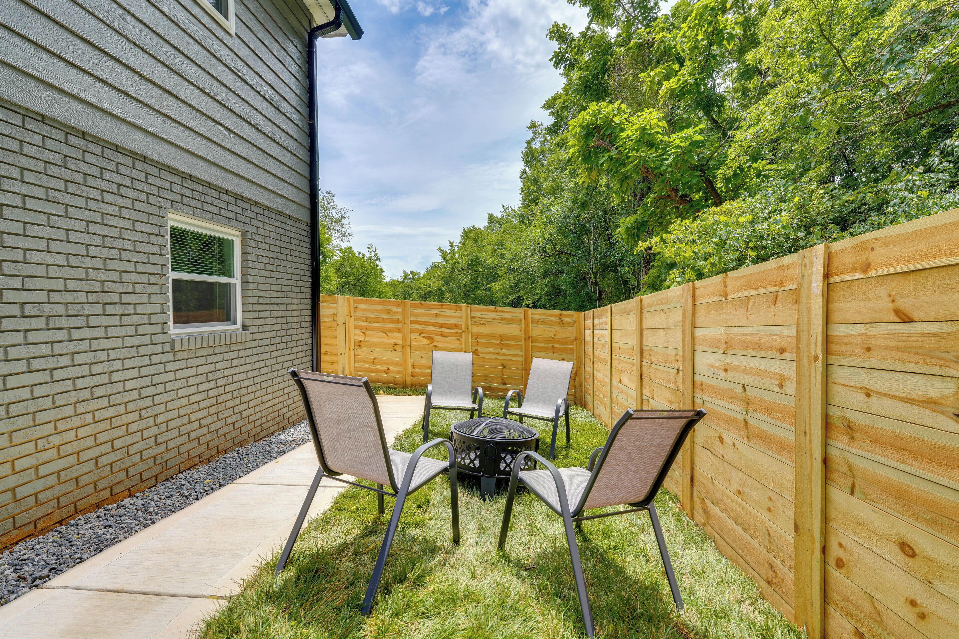 A backyard with a brick house, a wooden fence, and a table with chairs.