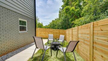 A backyard with a brick house, a wooden fence, and a table with chairs.