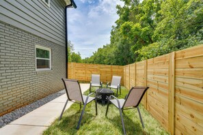 A backyard with a brick house, a wooden fence, and a table with chairs. - Rolling Hills Retreat, Cozy 2BR Near Lakes/smokies (Morristown)