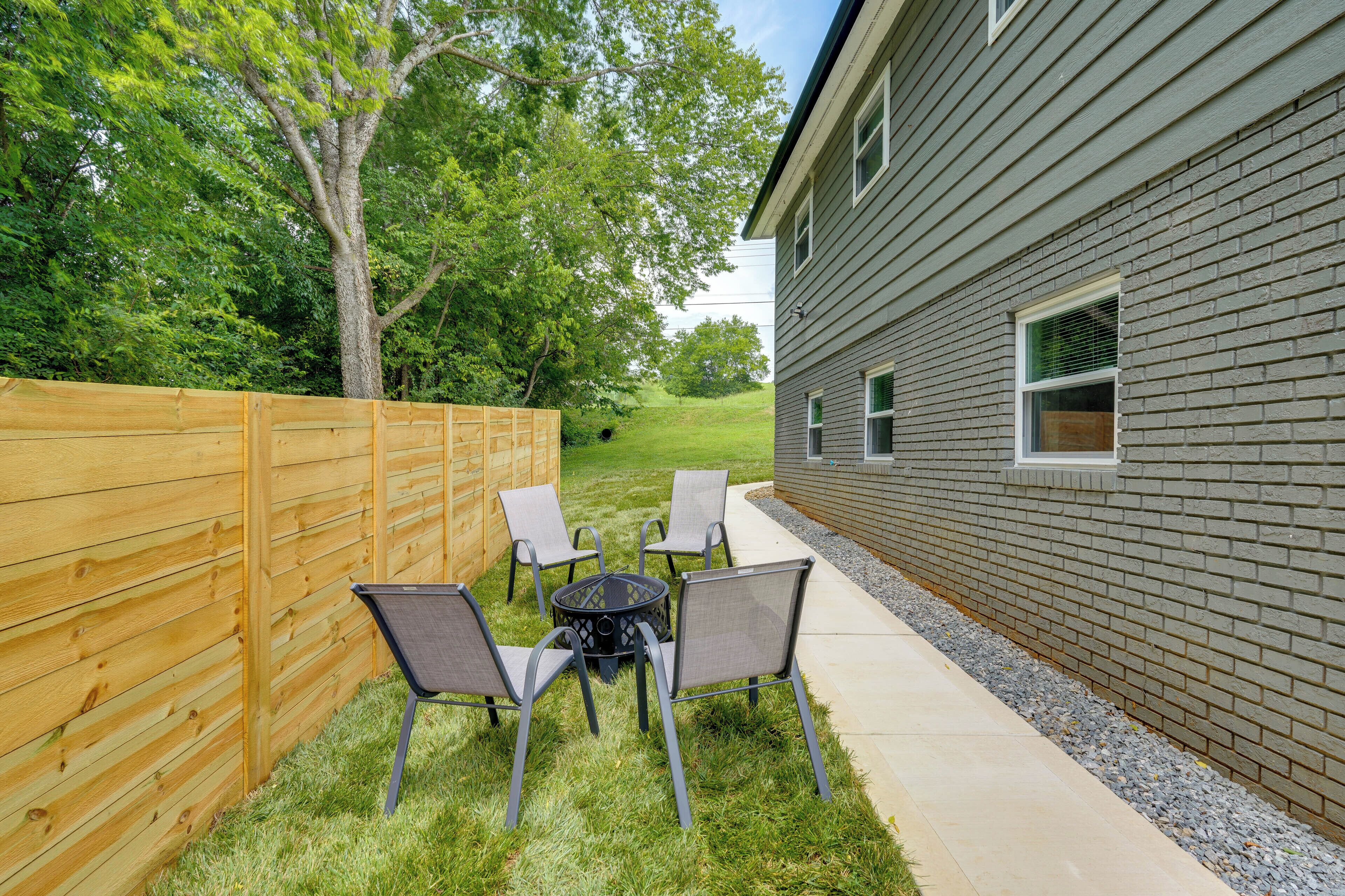 A patio with a round table and four chairs, a wooden fence, and a house with a brick exterior.