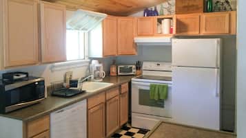 A compact kitchen with wooden cabinets, a microwave, a toaster, a sink, and a refrigerator.