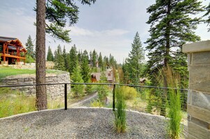 A view from a balcony overlooking a gravel path leading through a forested area with a stone wall and a wooden building.