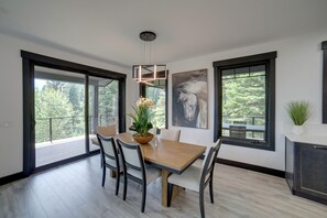 A modern dining room with a wooden table, chairs, and a potted plant.