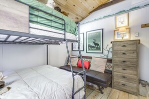 Ein Stockbett mit einer grünen Matratze, eine Holzkommode und ein gerahmtes Bild eines Elchs.