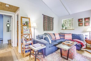 Ein gemütliches Wohnzimmer mit einem blauen Sofa, einem Couchtisch, einem Bücherregal und einem gemusterten Teppich.