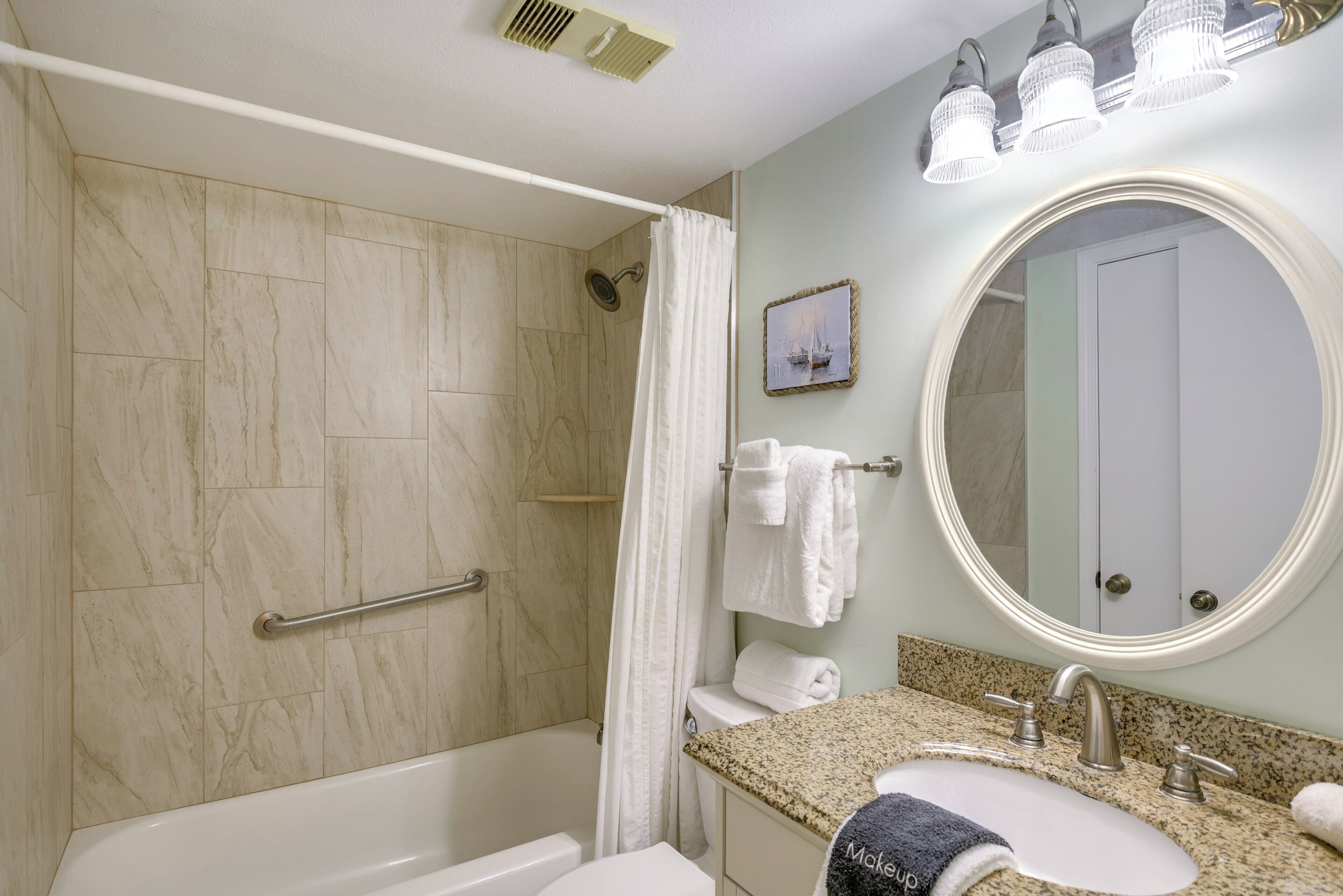 A bathroom with a bathtub, a shower, a vanity with a sink, a mirror, and a towel rack.