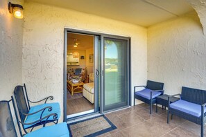 A covered patio area with a sliding glass door leading to an interior space, furnished with wicker chairs and a table. - Walk to Beach! Set of 2 St Augustine Condos (St. Augustine)
