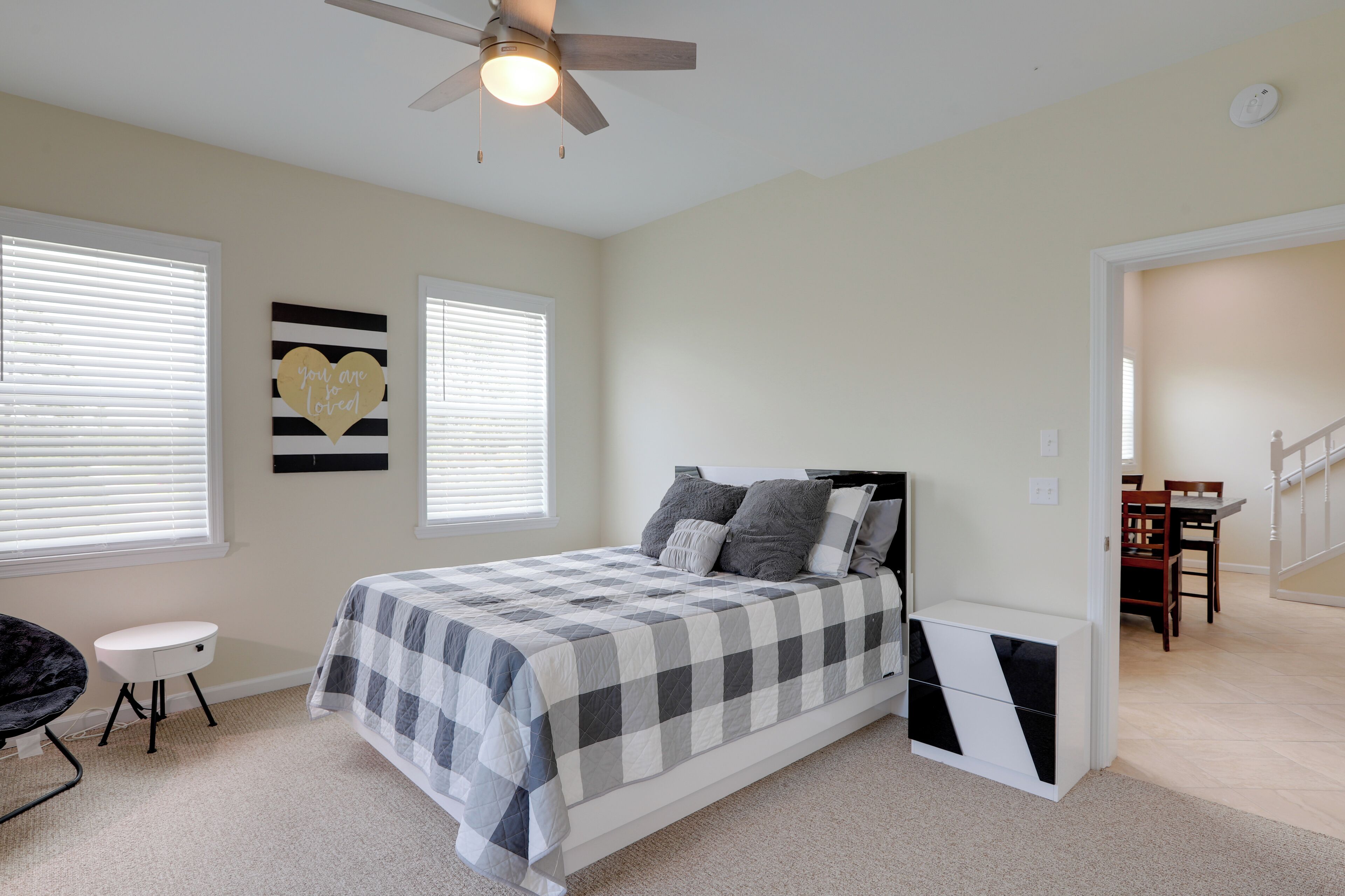 A bedroom with a bed, a ceiling fan, a desk, and a chair.