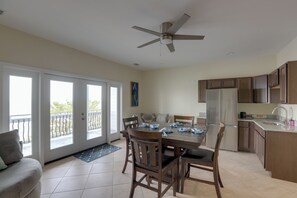A modern kitchen with a central island, a dining area with a table and chairs, and a ceiling fan. - Waterfront Family Home w/ Views in Carrabelle (Carrabelle)