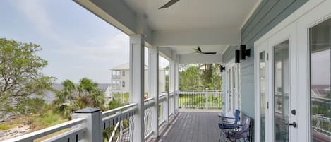 A covered porch with a ceiling fan, a railing, and a view of the ocean.