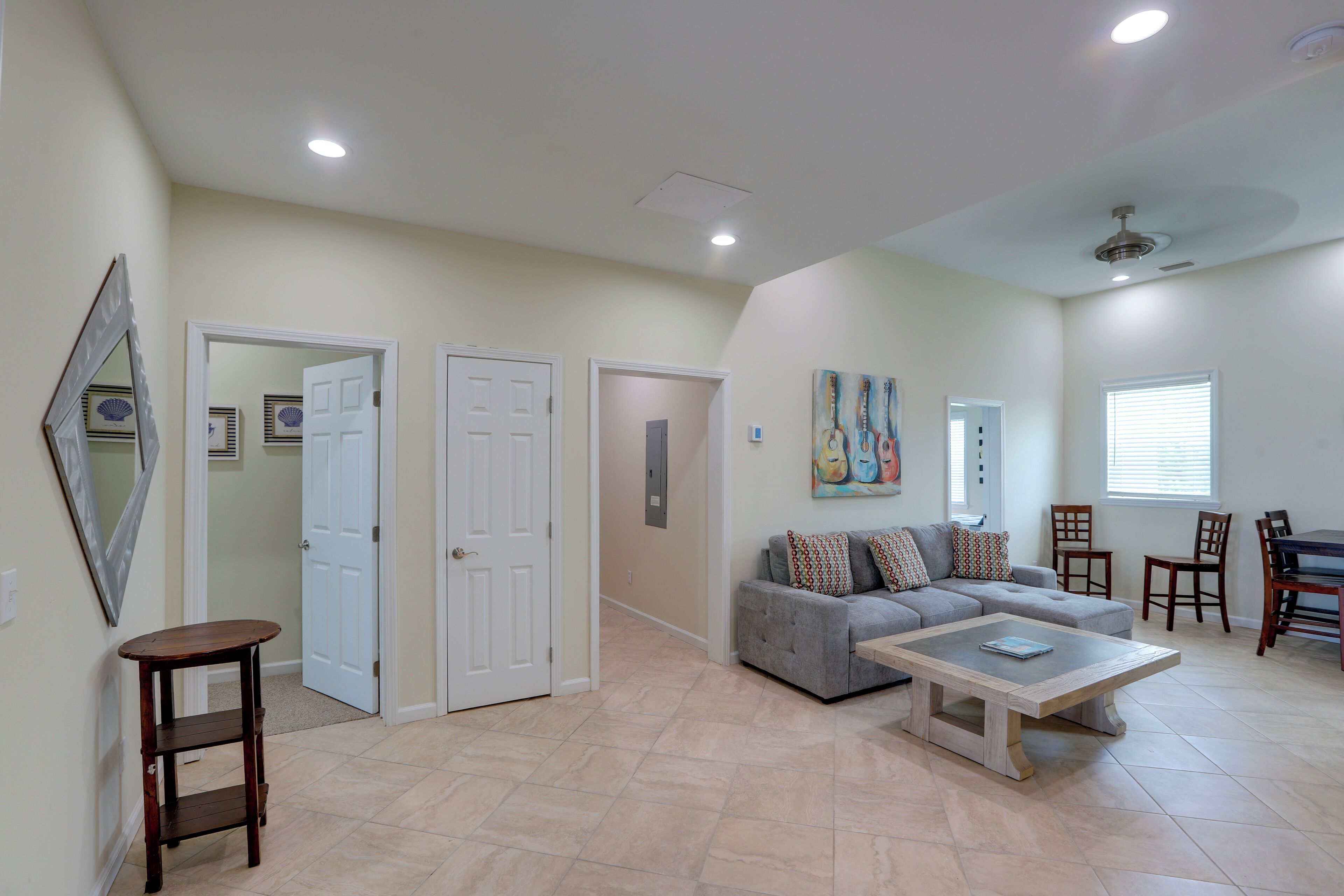 A spacious living room with a grey sofa, a coffee table, and a dining area with chairs.