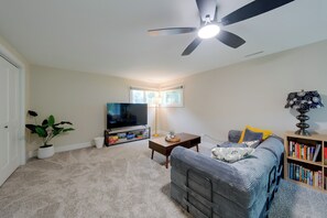 A living room with a ceiling fan, a flat-screen TV, a bookshelf, a coffee table, and a sofa.
