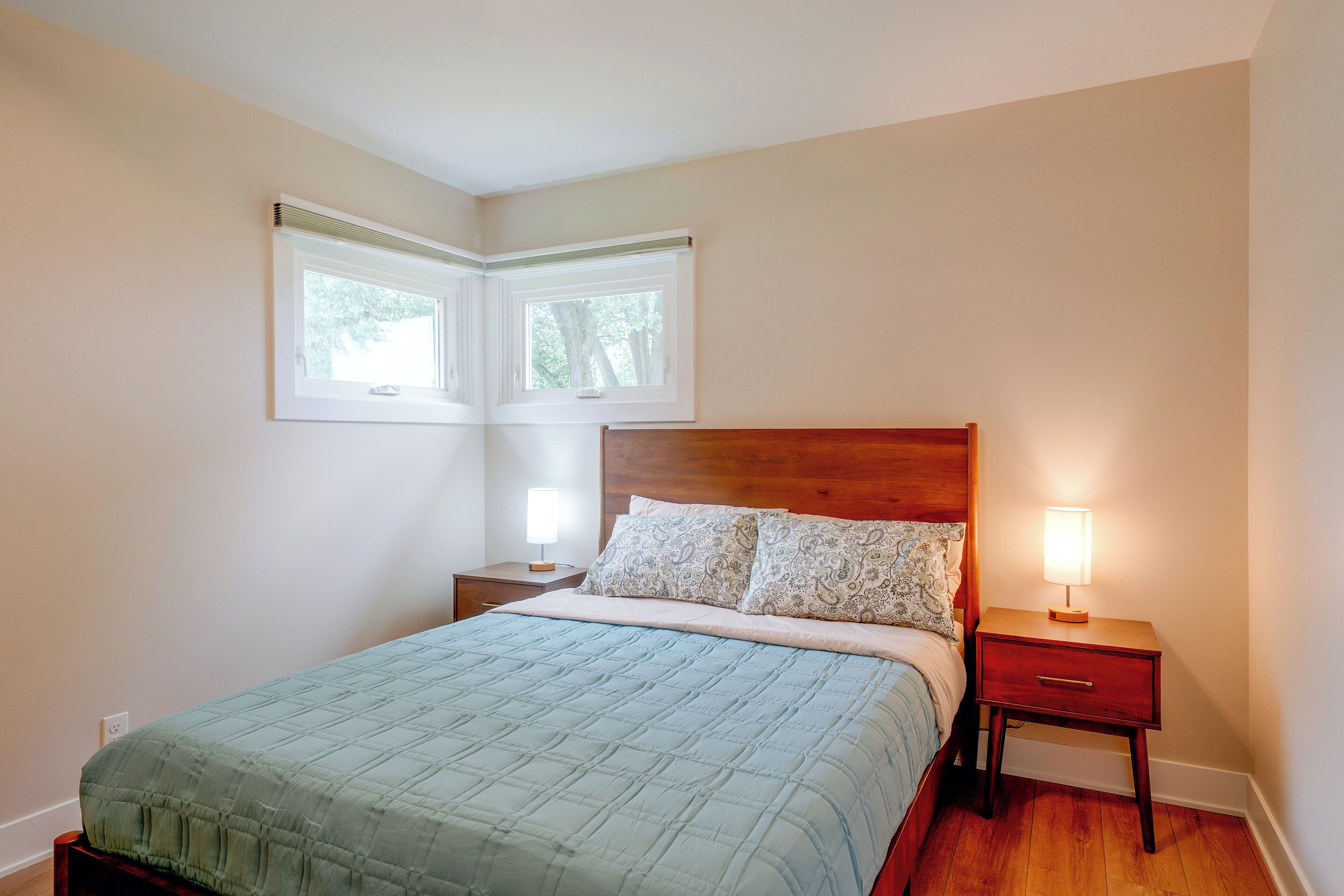 Een slaapkamer met een bed, twee nachtkastjes, een raam en een deur.