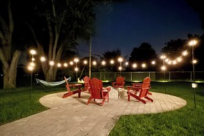 Een terras met rode stoelen en een tafel, omgeven door een metselpad en lichtslingers.