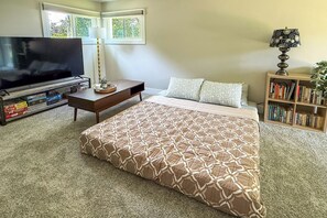 Un dormitorio con una cama grande, televisión, estantería y ventana con vistas.