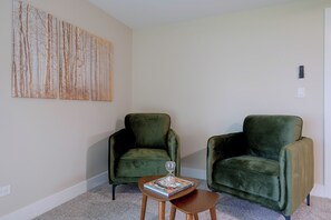 A room with two green armchairs, a small wooden table with a book, and a wall-mounted light switch. - Walk to Beach! Mccullom Lake Family Getaway (McHenry)