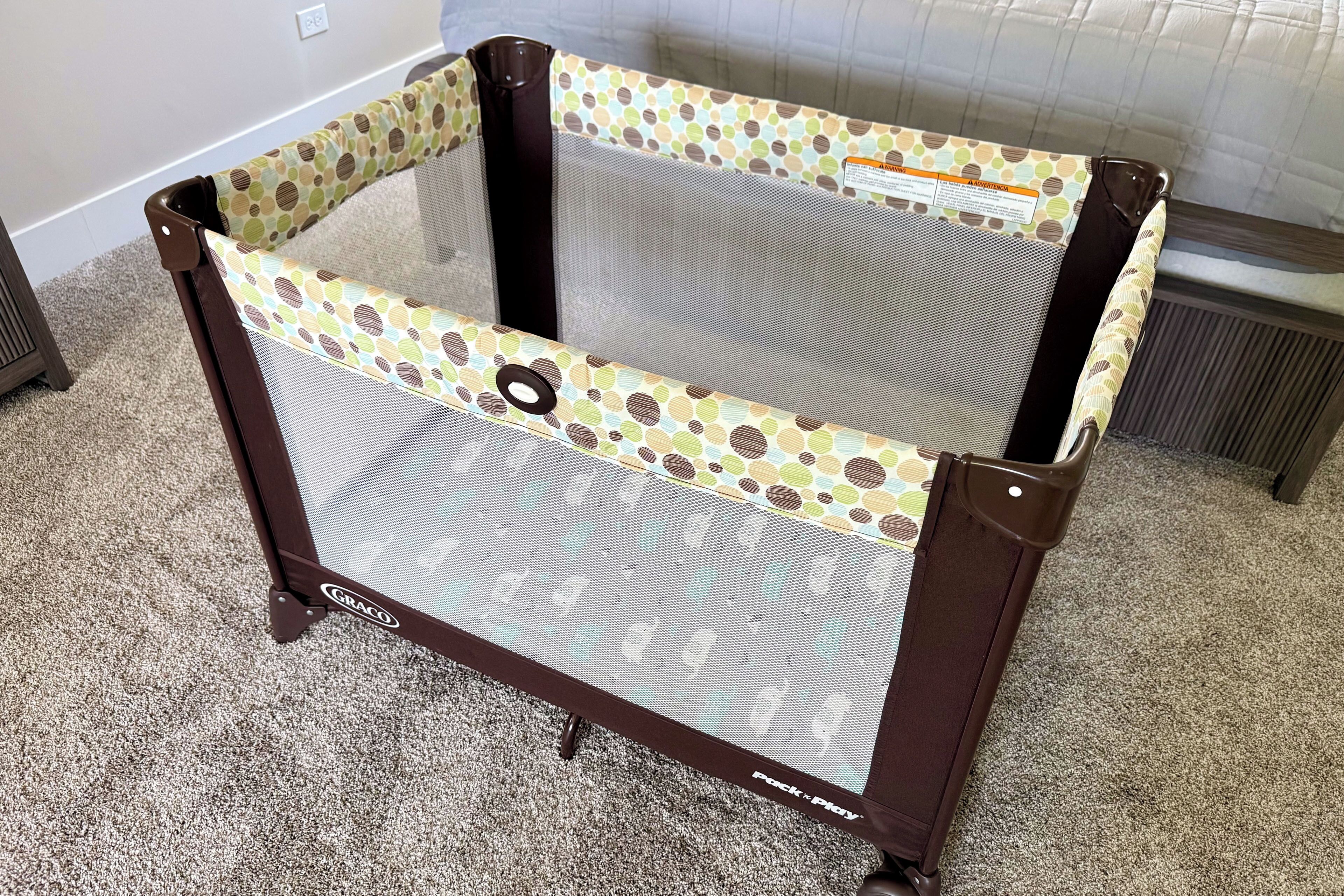 A baby playpen with a polka dot pattern and the brand name 'Graco' visible on the side.