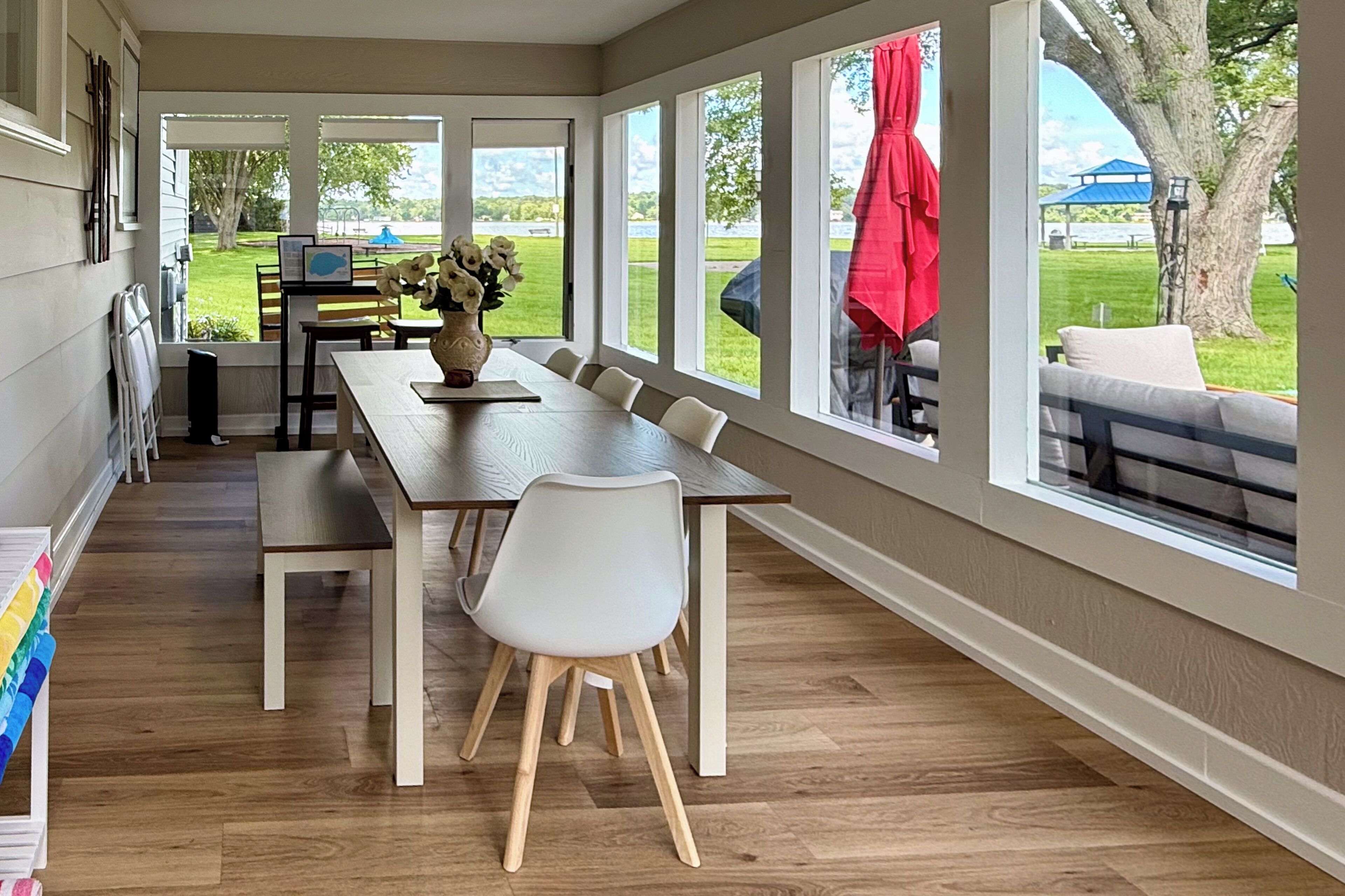 Un espace repas avec une longue table, des chaises et un vase de fleurs.