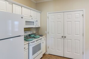 A kitchen with white cabinetry, a refrigerator, a microwave, and a stove.