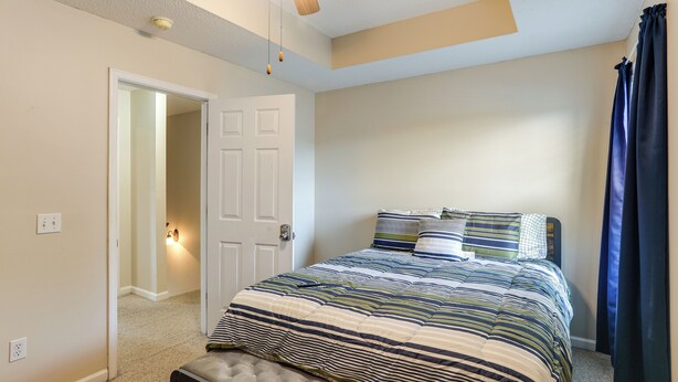 Un dormitorio con cama, puerta, interruptor de luz y ventilador de techo.