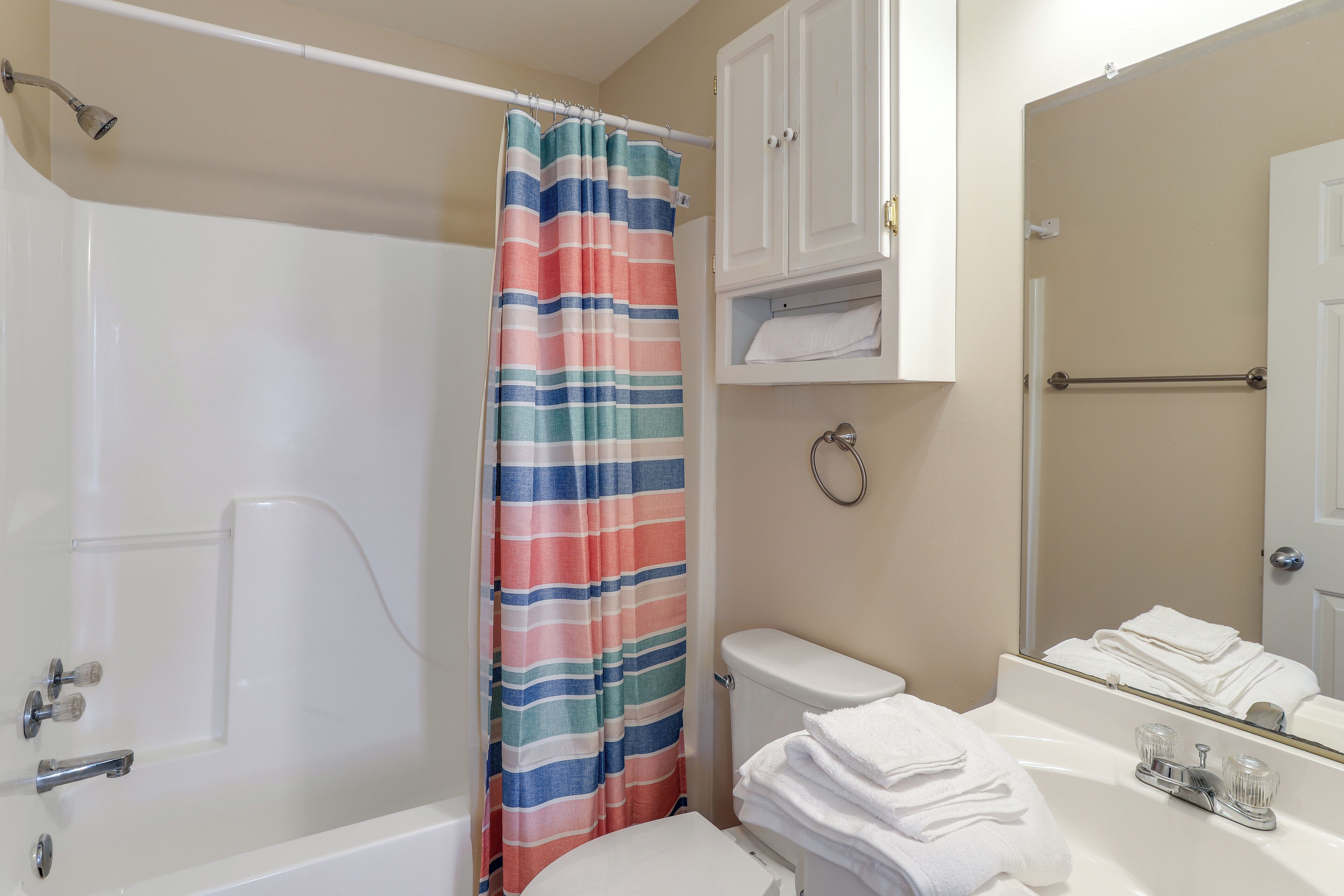 A bathroom with a bathtub, toilet, and a sink with a mirror.