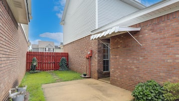 A residential backyard with a brick wall, a red wooden fence, and a small garden area with potted plants.