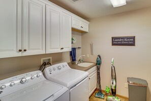 A laundry room with a washing machine, dryer, sink, and a sign indicating where to drop off laundry. - Private Dock & Hot Tub! Big Stone Lake Getaway (Ortonville)