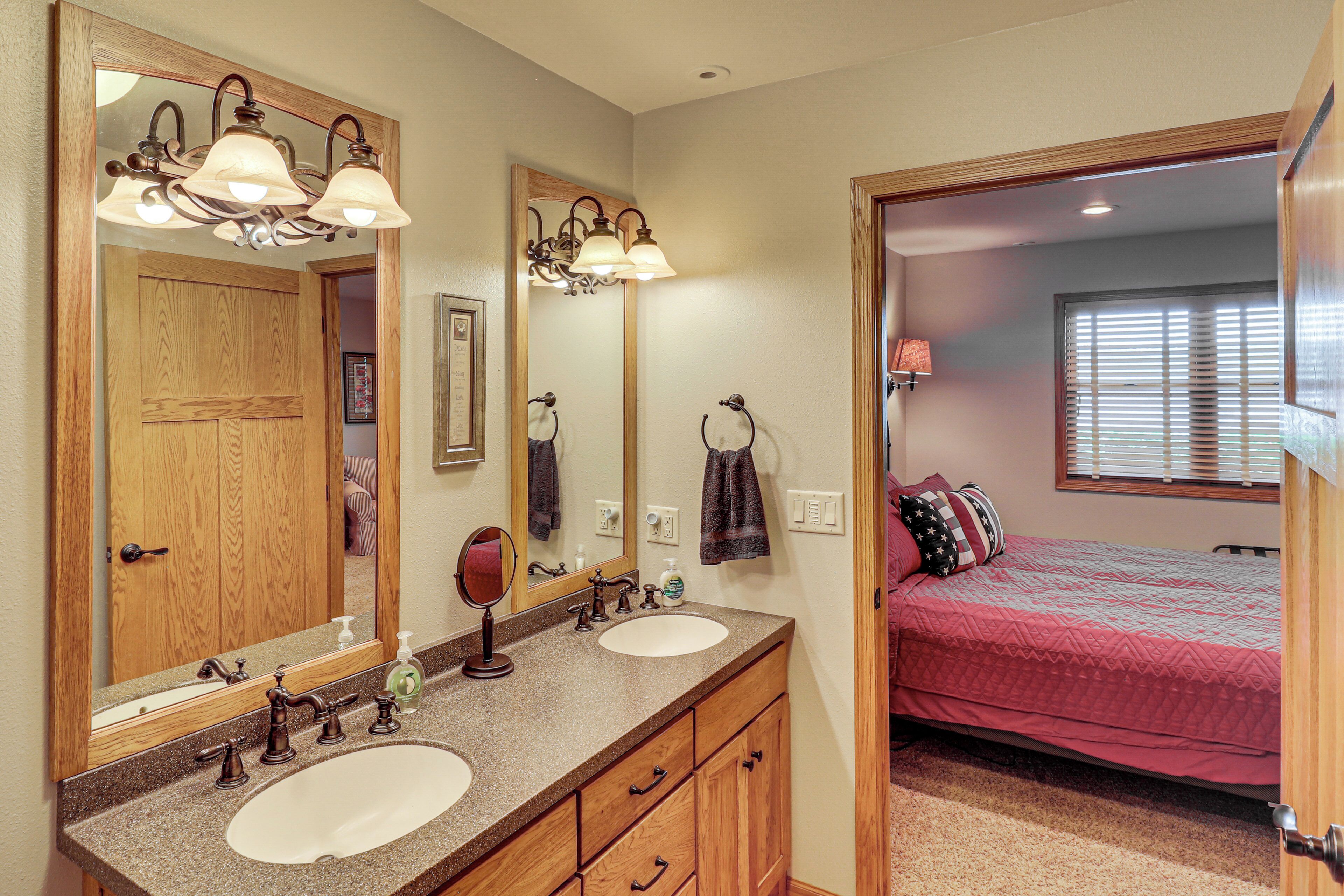 A bathroom with two sinks, a mirror, and a vanity with wooden cabinets.