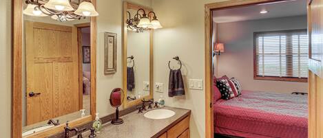 A bathroom with two sinks, a mirror, and a vanity with wooden cabinets.
