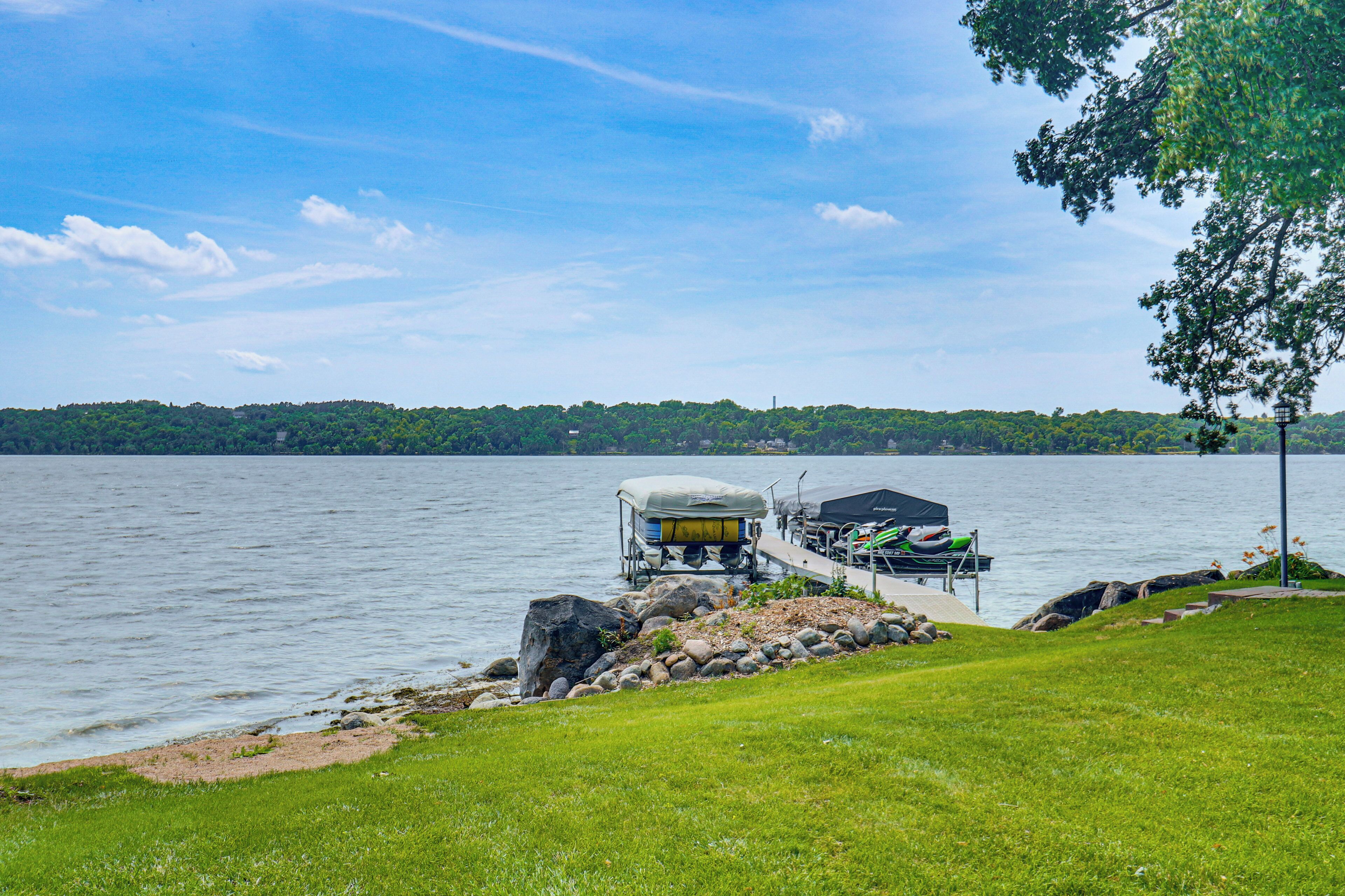 A lakeside dock with a covered boat and a kayak.