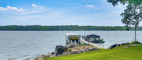 A lakeside dock with a covered boat and a kayak.