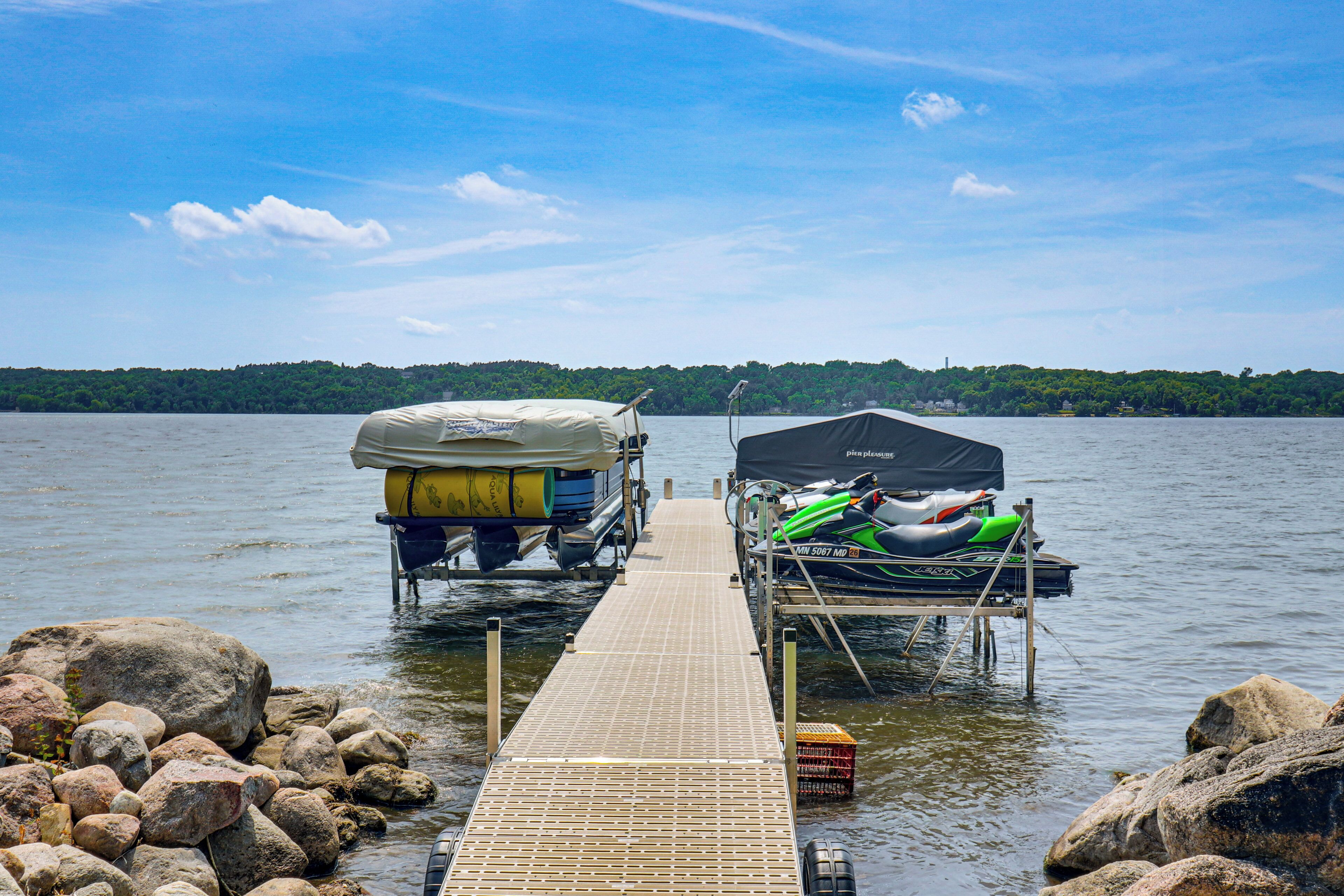 A wooden dock extending into a lake with a rowboat and a motorboat docked at the end.