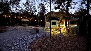 A rustic cabin with a covered porch, a fire pit, and a stone pathway leading to it.