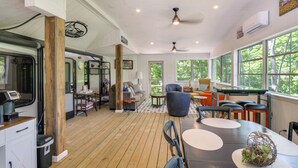 Een ruime kamer met een houten vloer, een pooltafel en een zithoek met een bank en stoelen.