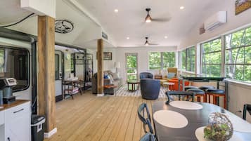 A spacious room with a wooden floor, a pool table, and a seating area with a sofa and chairs.